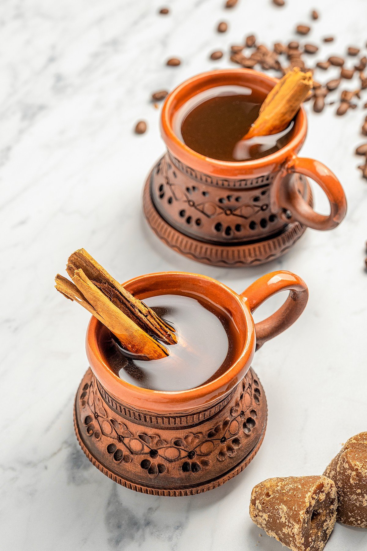 Two clay mugs full of Café de Olla with cinnamon sticks.