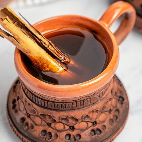 A clay mug filled with Café de Olla with a cinnamon stick.