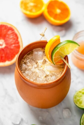 A Cantaritos in a clay mug with lots of ice and citrus garnish.