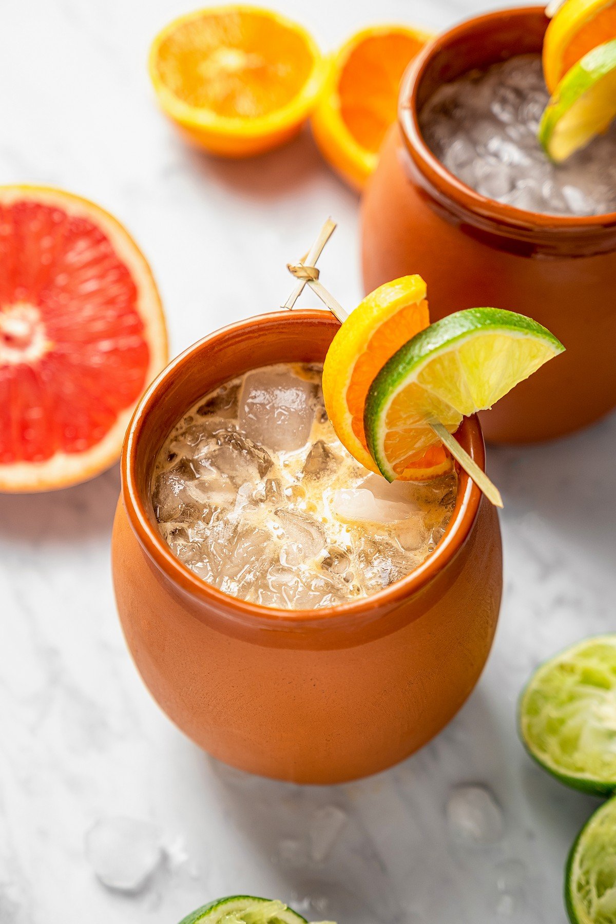 Cantaritos in a clay mug with a lime and orange wedge for garnish.