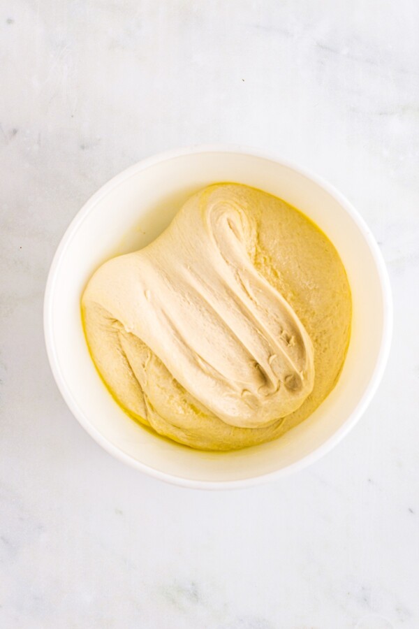 Stretching and folding dough in a mixing bowl.