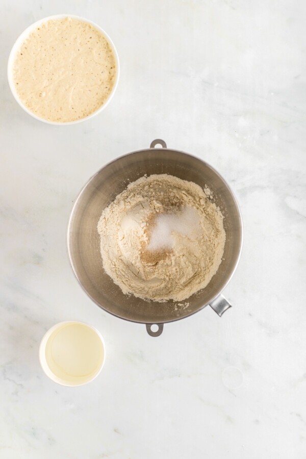 Combining dough ingredients in a stand mixer bowl.