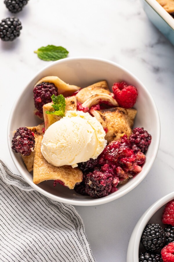 A bowl of classic berry cobbler with ice cream on top.