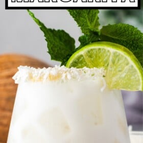 A fruity coconut margarita with a lime wedge and fresh mint for garnish.