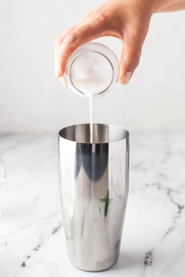 Coconut milk being poured into a cocktail shaker.