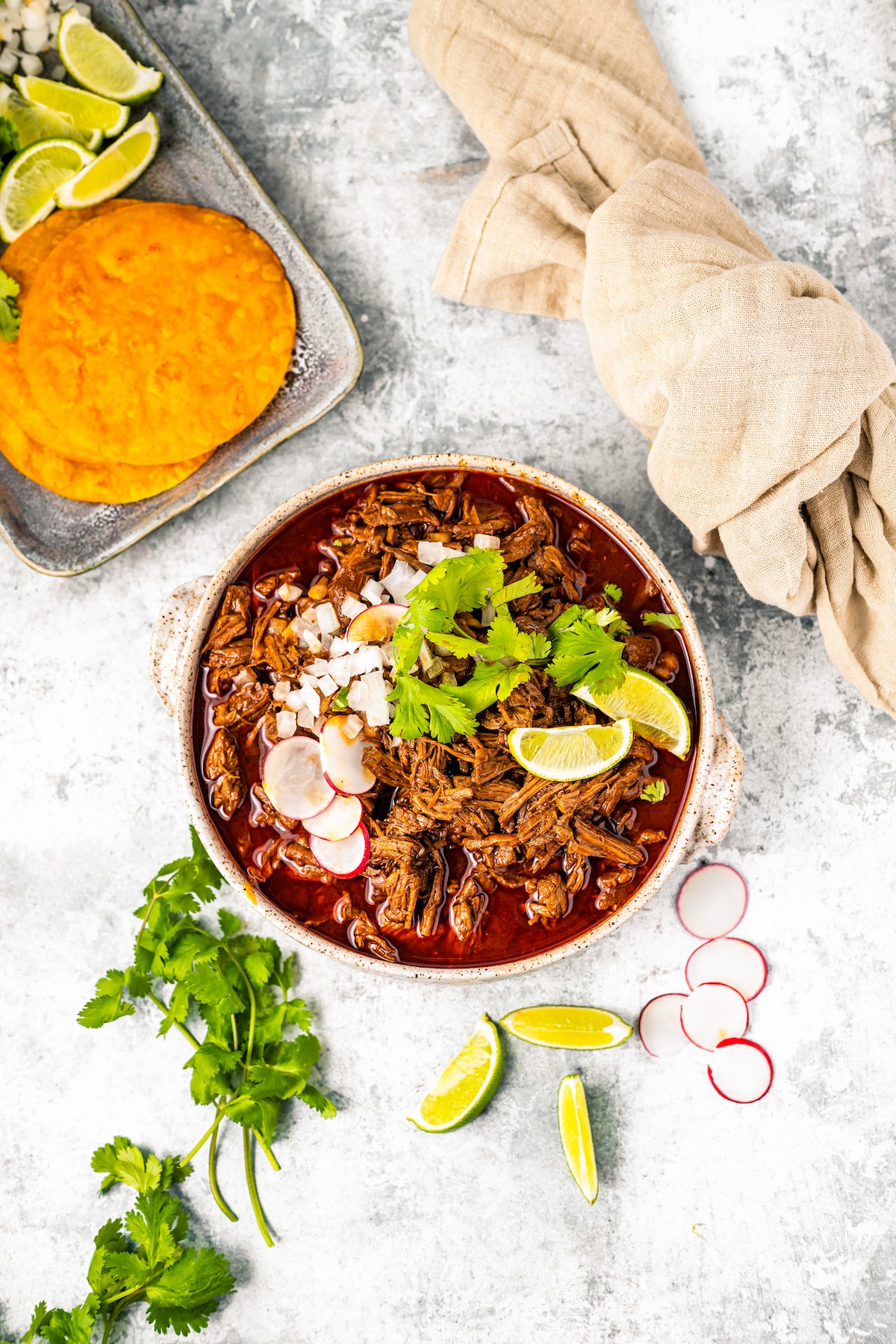 Overhead photo of crockpot birria in a bowl with tortillas on the side.