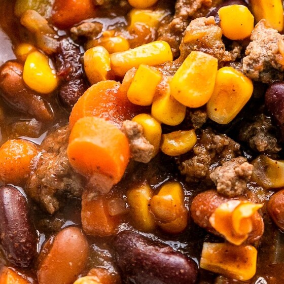 A bowl of slow cooker chili with beans, corn and carrots.