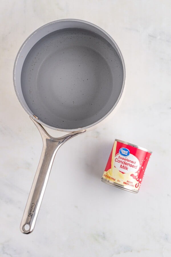 A saucepan next to a can of sweetened condensed milk.
