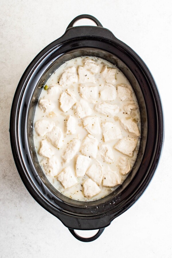 Adding biscuit pieces to slow cooker.