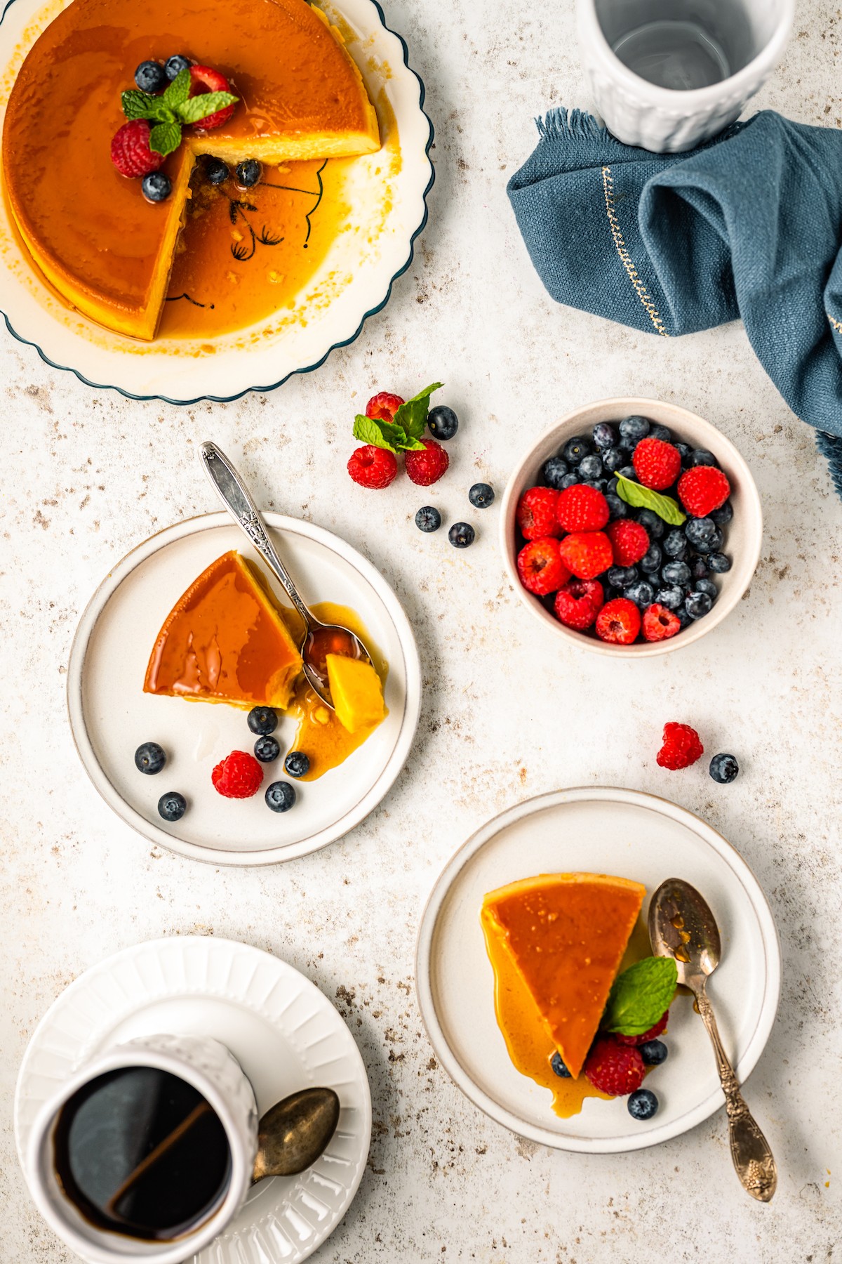 Sliced flan on plates with a bowl of berries on the side. 
