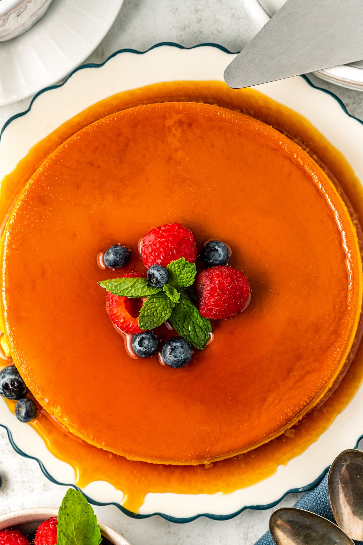 Overhead shot of whole flan de queso garnished with fresh berries.