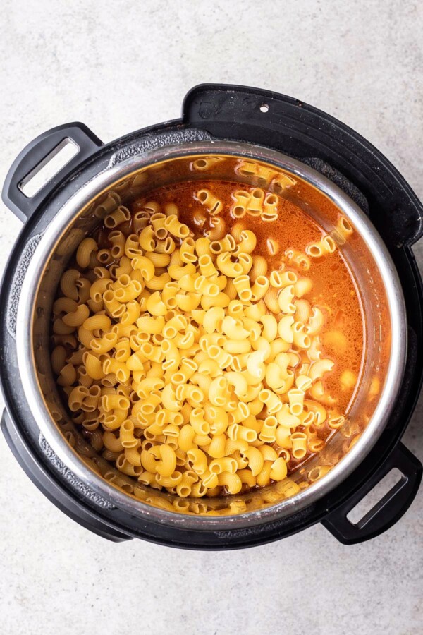 Dry macaroni elbows added to a pressure cooker.