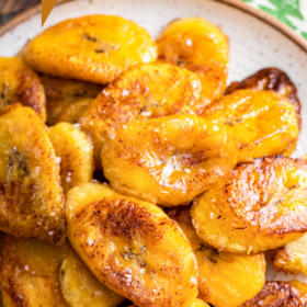 Pan fried plantains on a plate with salt sprinkled on top.