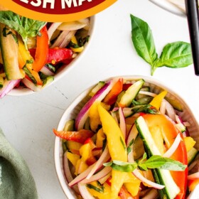 Three bowls of mango salad with forks.