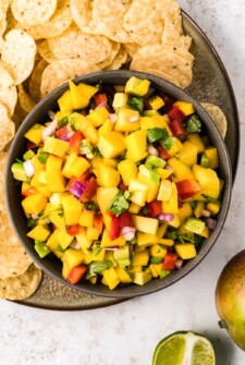 Bowl of mango salsa with corn chips on the side.