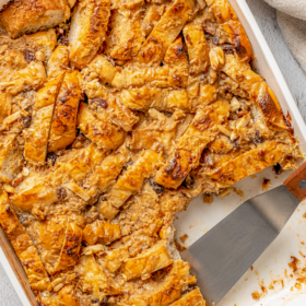 Mexican bread pudding in a baking dish with a spatula cutting servings.