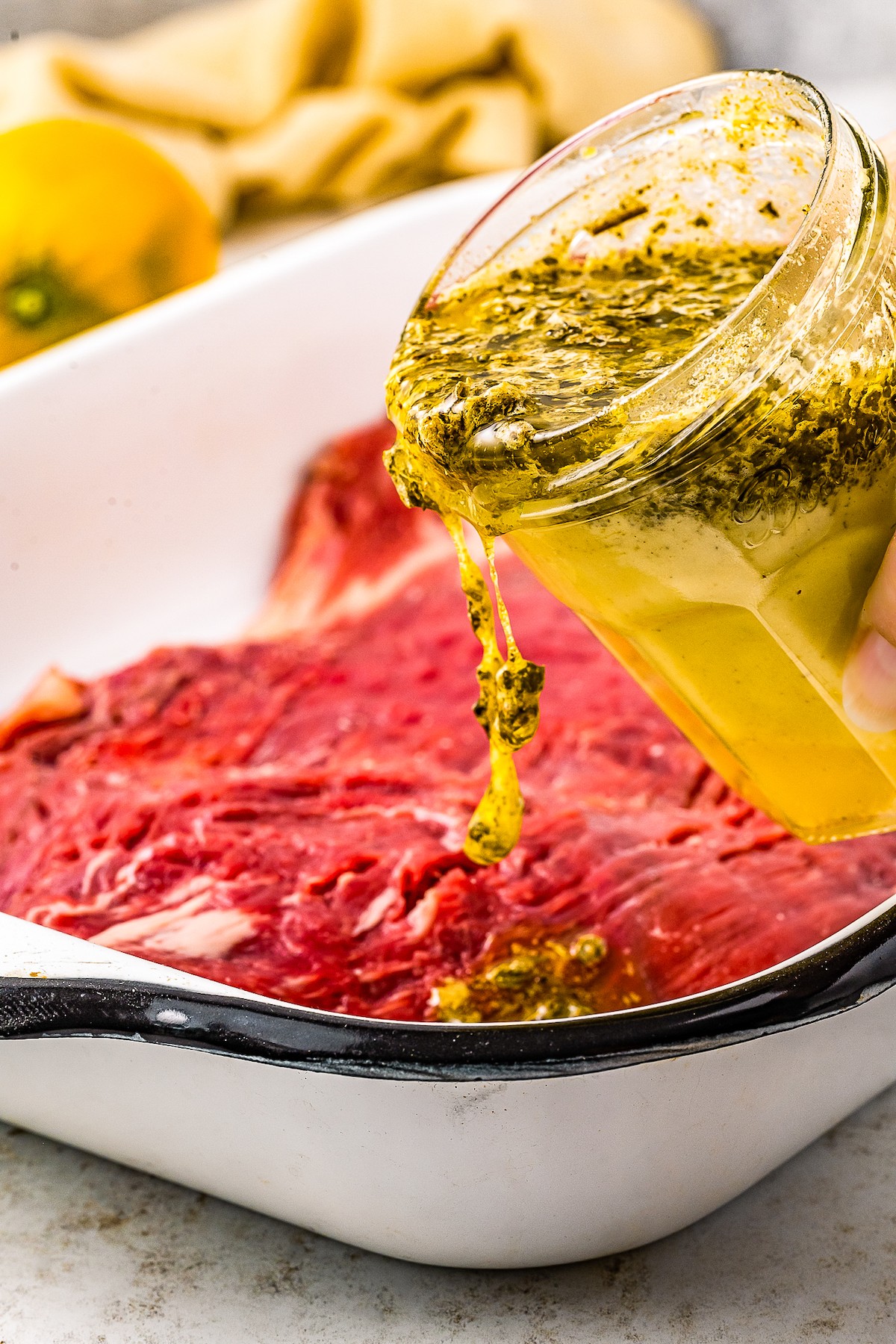 Pouring marinade over steak.