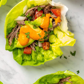 Shredded Mexican Chilled Beef Salad wrapped in lettuce with a homemade chile sauce drizzled on top.