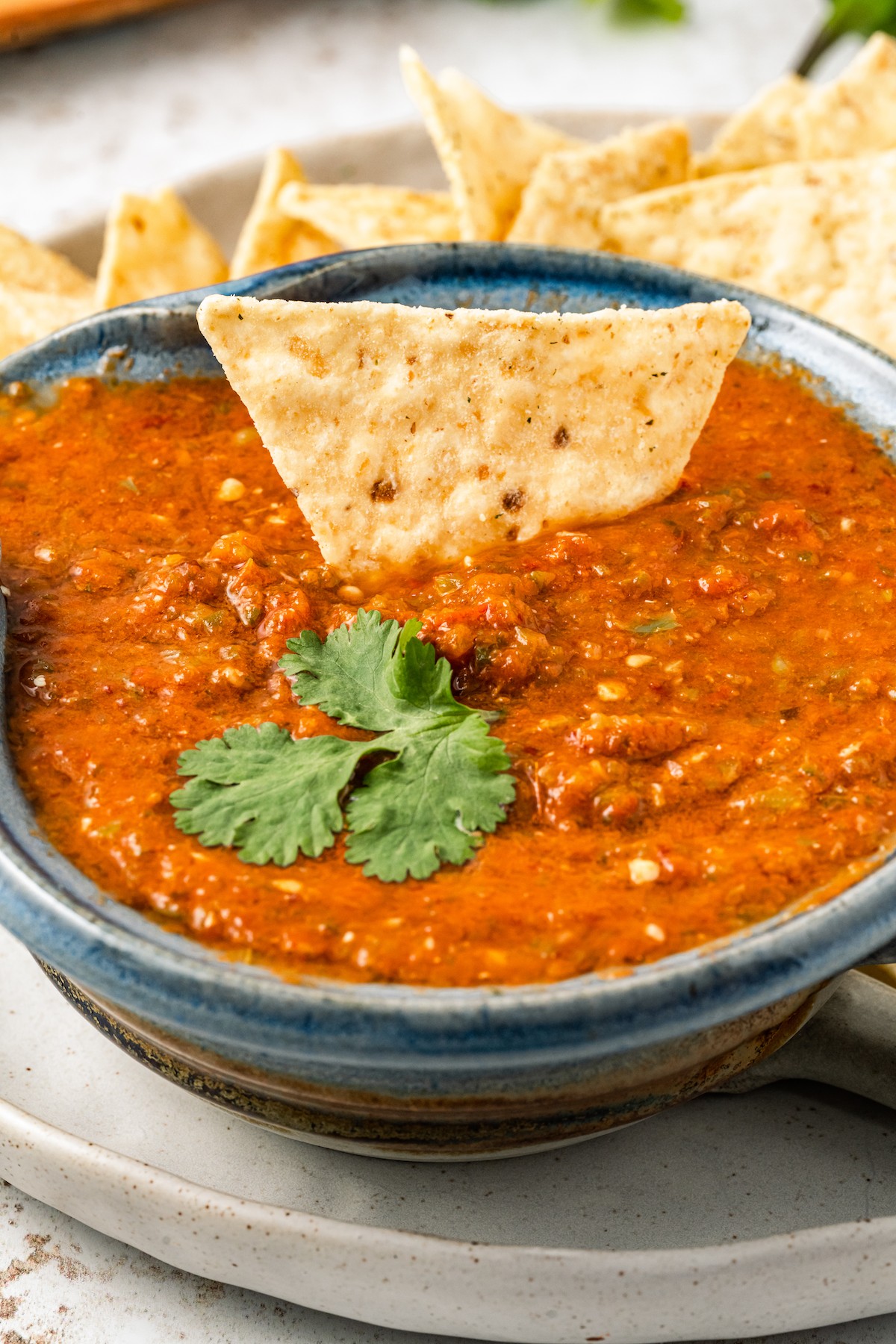 Bowl of salsa ranchera with a tortilla chip in it. 