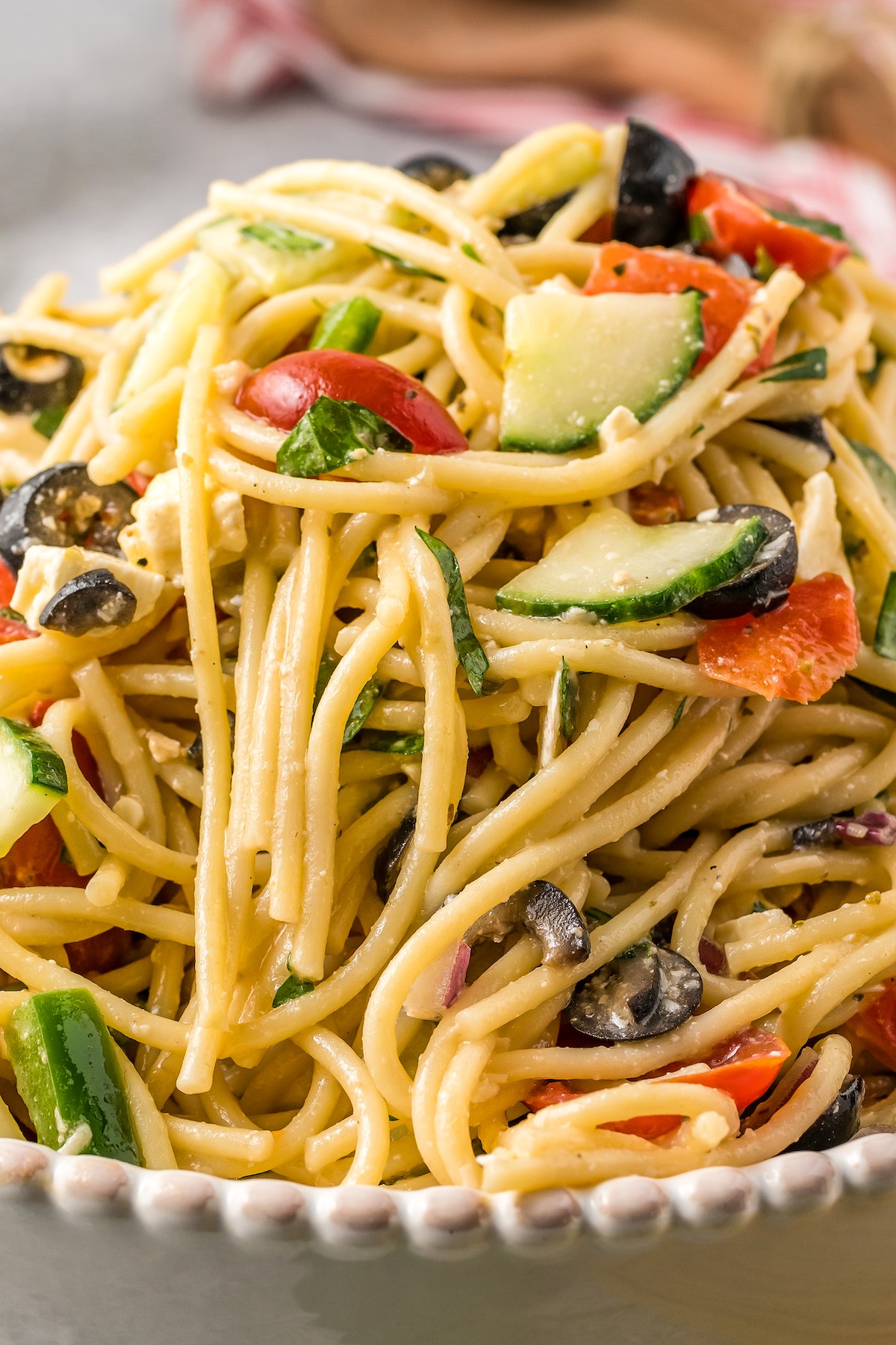 Close-up shot of cold spaghetti noodles with salad dressing and veggies.