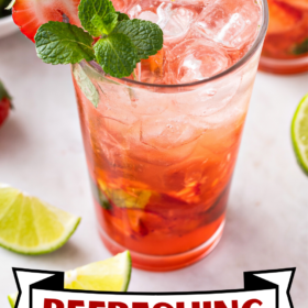 A strawberry mojito with strawberry and mint garnish on the rim of the glass.