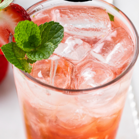 A strawberry mojito in a high ball glass with fresh mint.