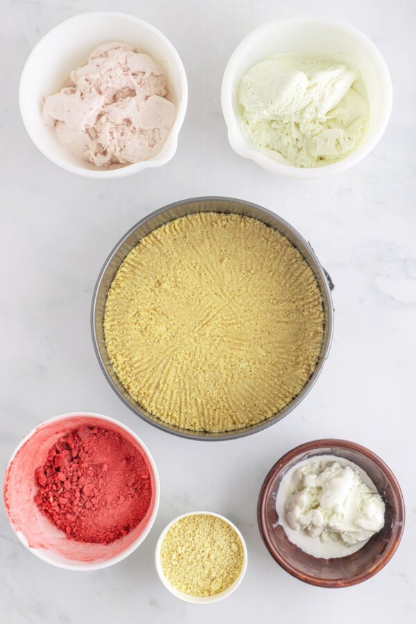 Ingredients for an ice cream cake arranged around a springform pan with a cookie crust.