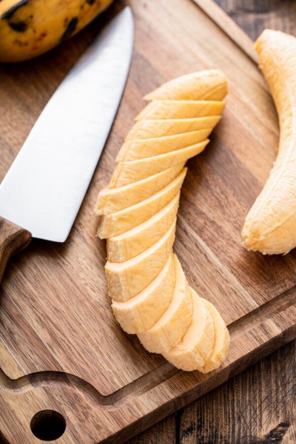 A plantain sliced into pieces on a cutting board.