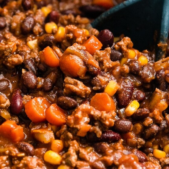 A pot of the best chili being scooped up with a serving spoon.