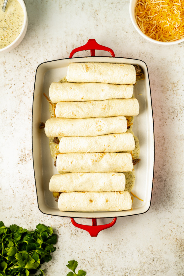 Assembling the enchiladas and placing them in the baking pan.