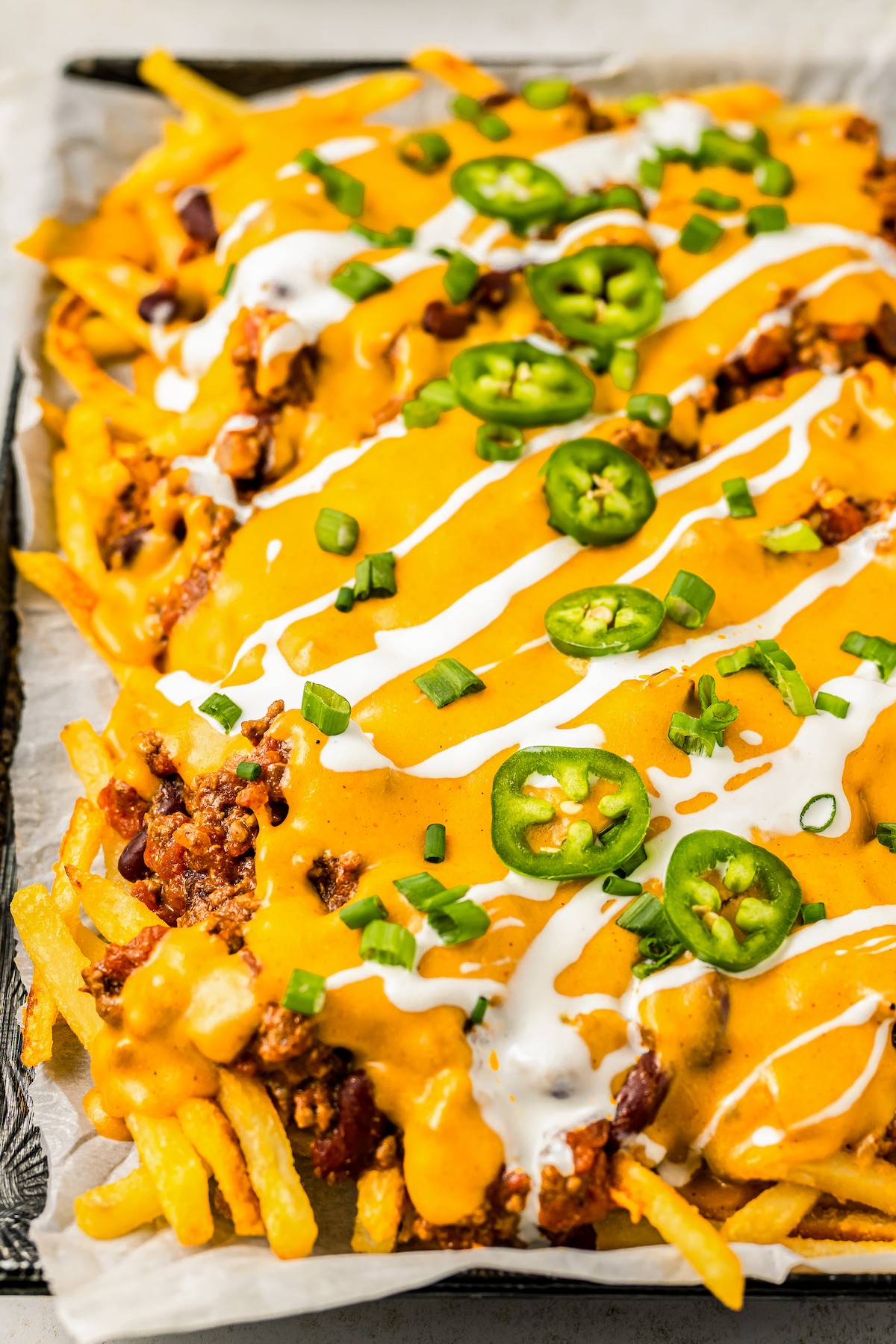 A baking sheet lined with parchment and covered with chili cheese fries.