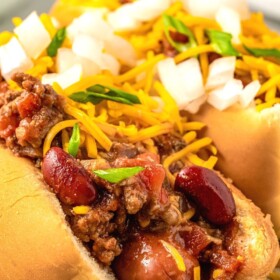 Hot dog chili on top of a hot dog with cheese.