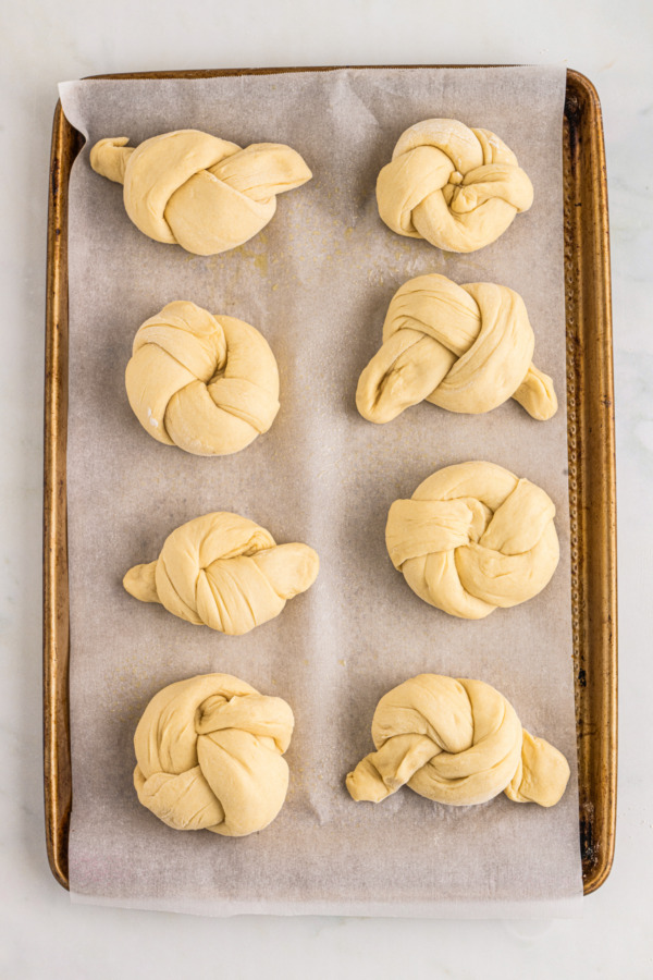 Unbaked knots of dough on a baking sheet.