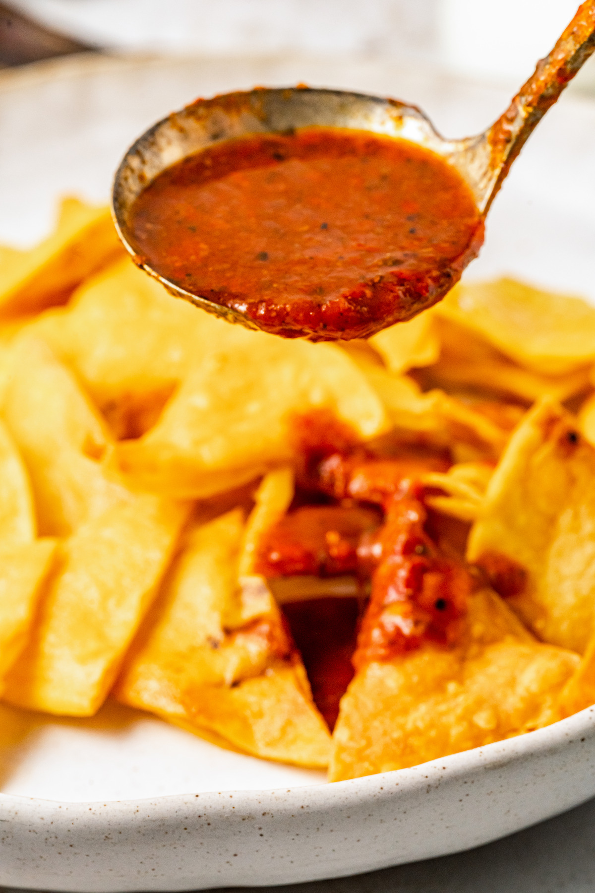 Pouring salsa over tortilla chips.