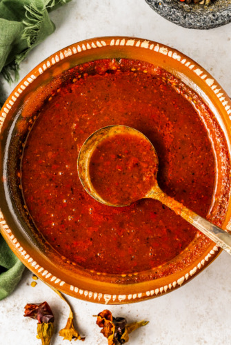 Bowl of guajillo sauce with a metal spoon.