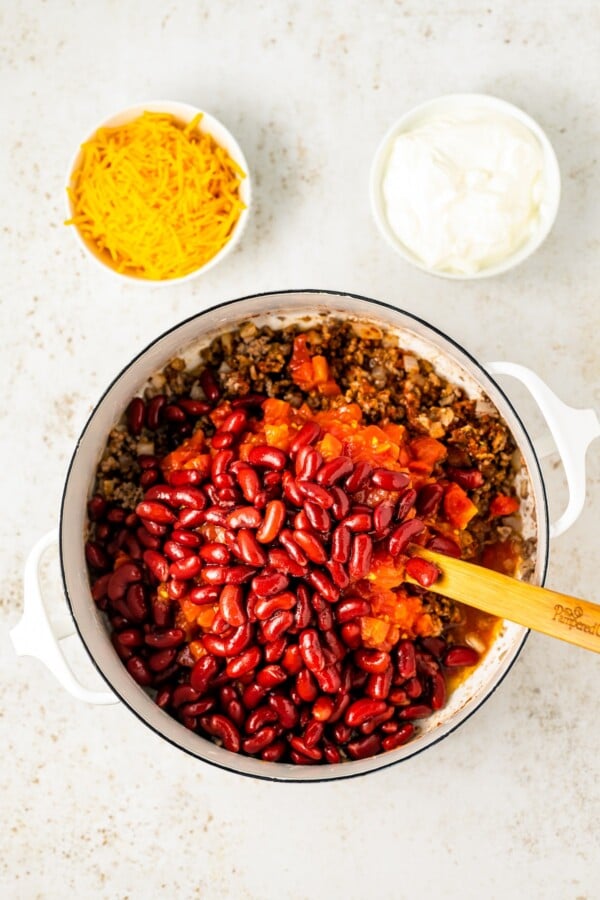 Mixing chili ingredients in a saucepan.