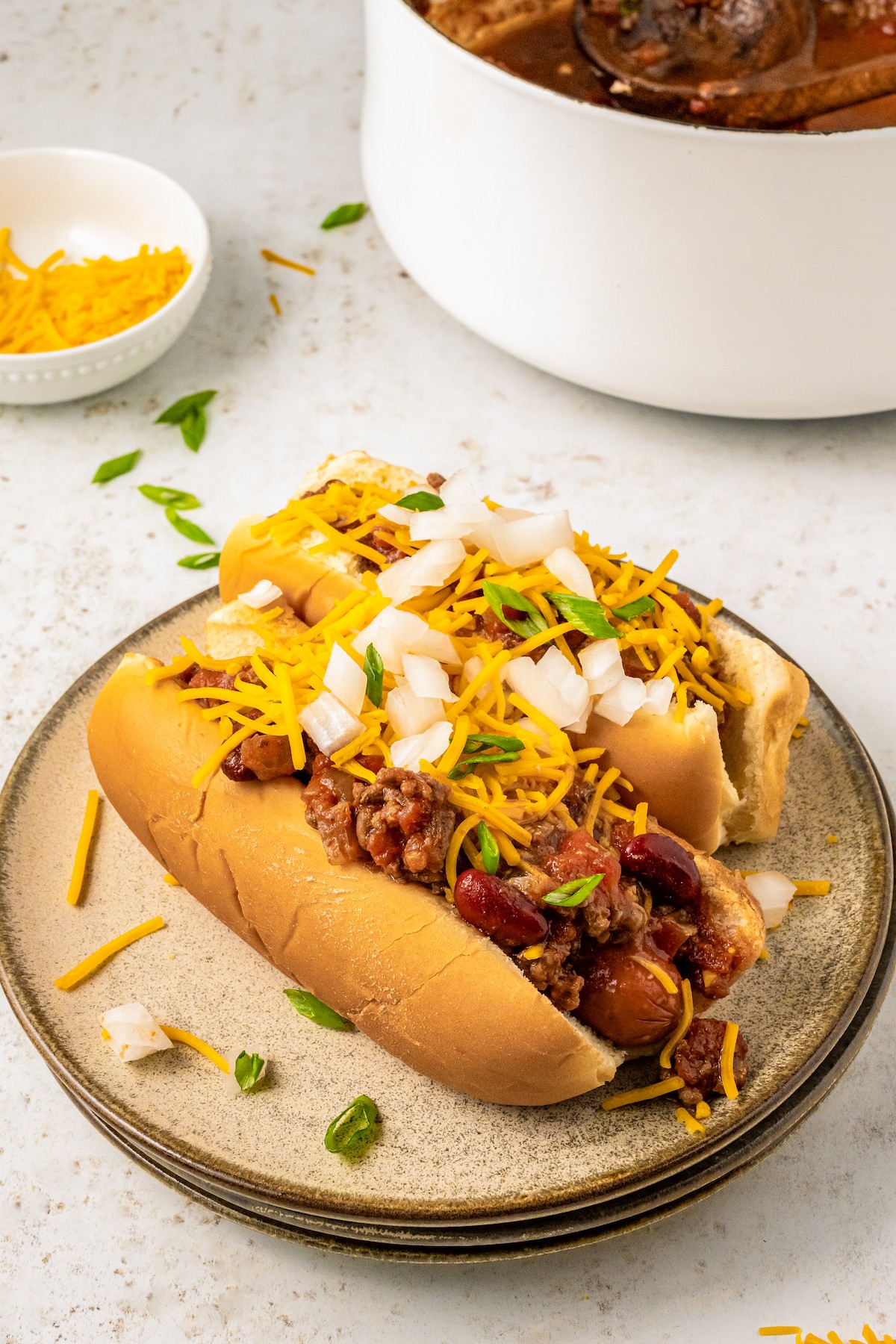 Chili dogs on a plate with toppings.