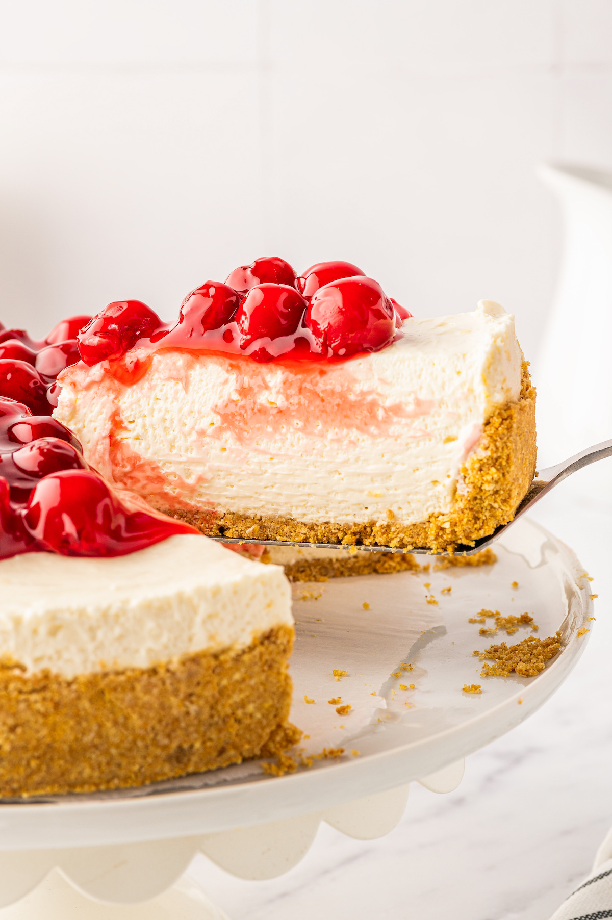 Lifting a slice of no-bake cherry cheesecake with a cake server.