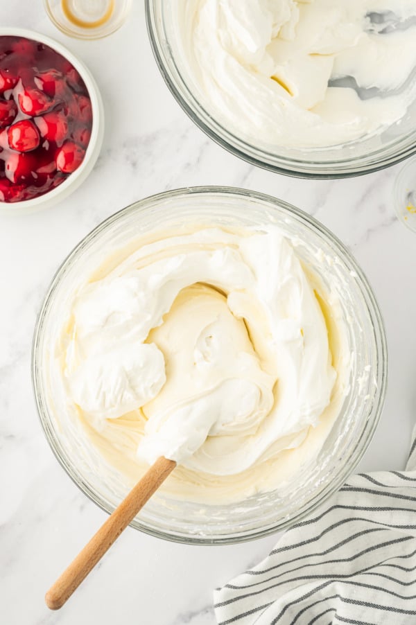 Folding whipped cream into cheesecake mixture.