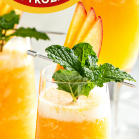 Peach Bellini garnished with fresh peaches and mint.