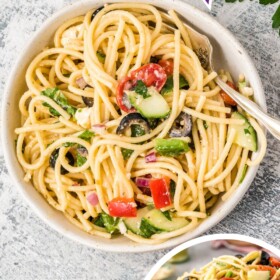 A bowl of Spaghetti Salad with cucumbers, olives and tomatoes.