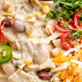 White chicken chili in a bowl with all the toppings piled on top.