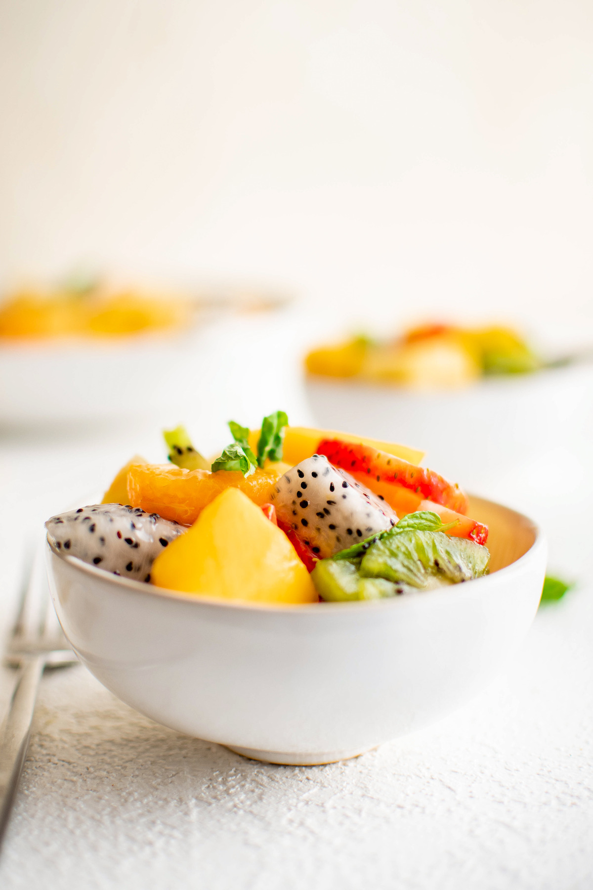 Tropical fruit salad in a small white bowl.