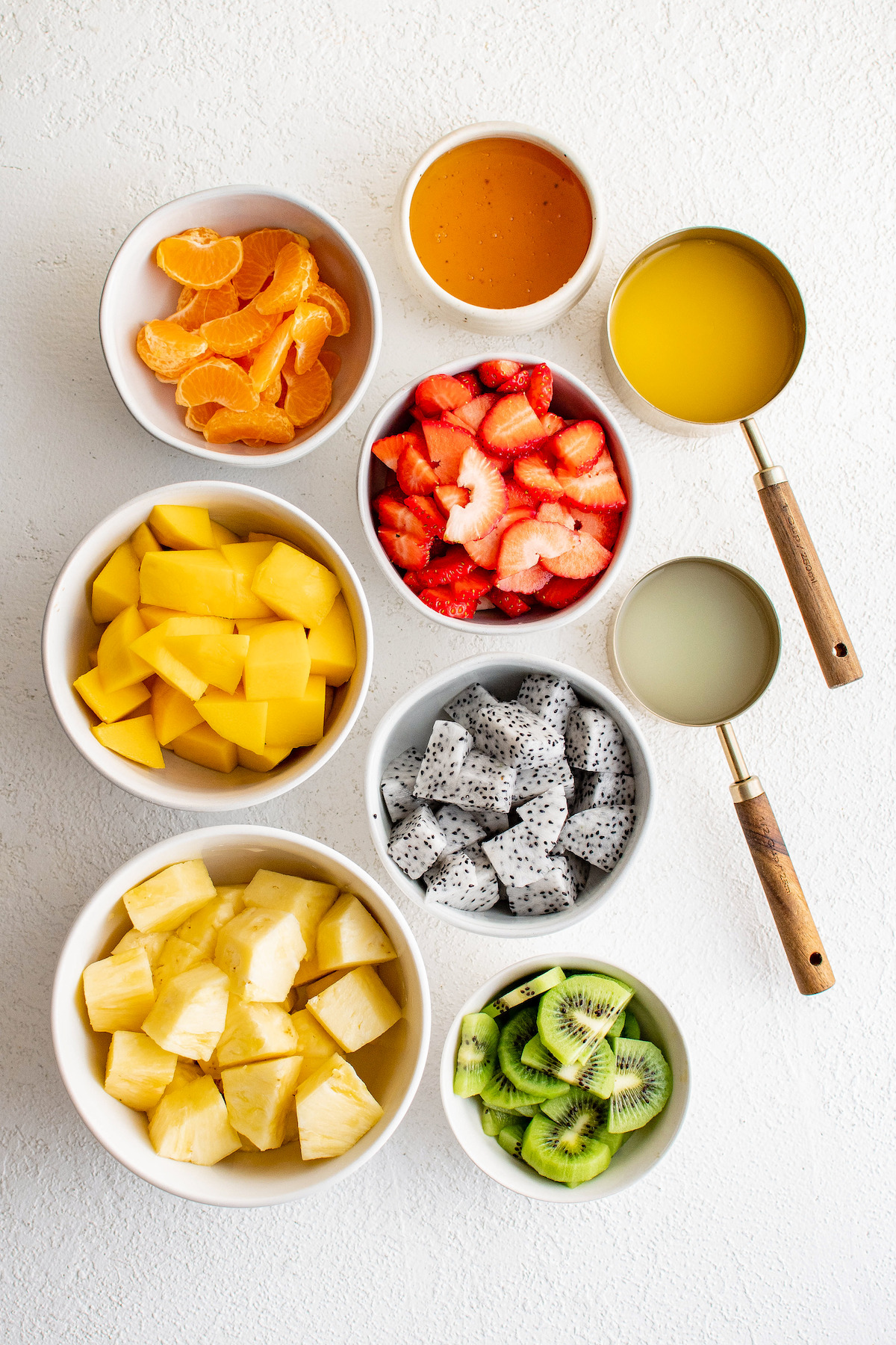 Ingredients for tropical fruit salad arranged on a work surface.