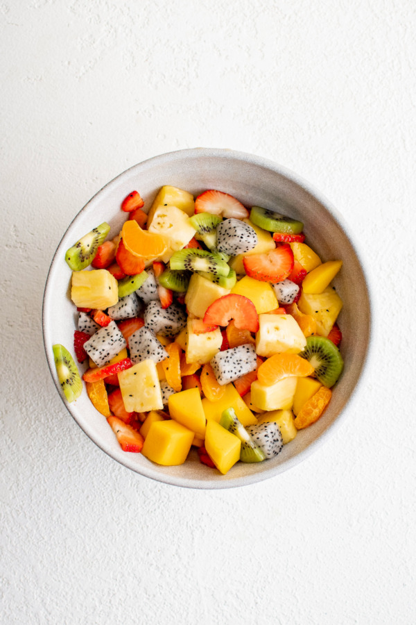 Kiwi, dragon fruit, strawberry, and other tropical fruit in a bowl.