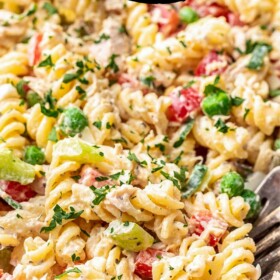 Easy tuna pasta salad with herbs sprinkled on top in a bowl with two forks.