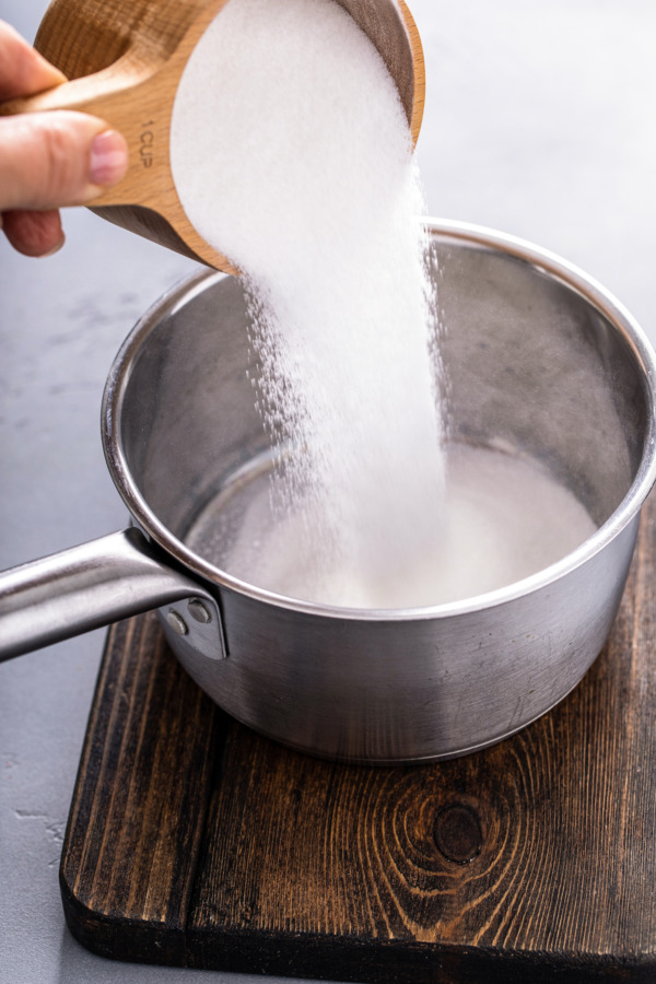 Pouring sugar into a saucepan.