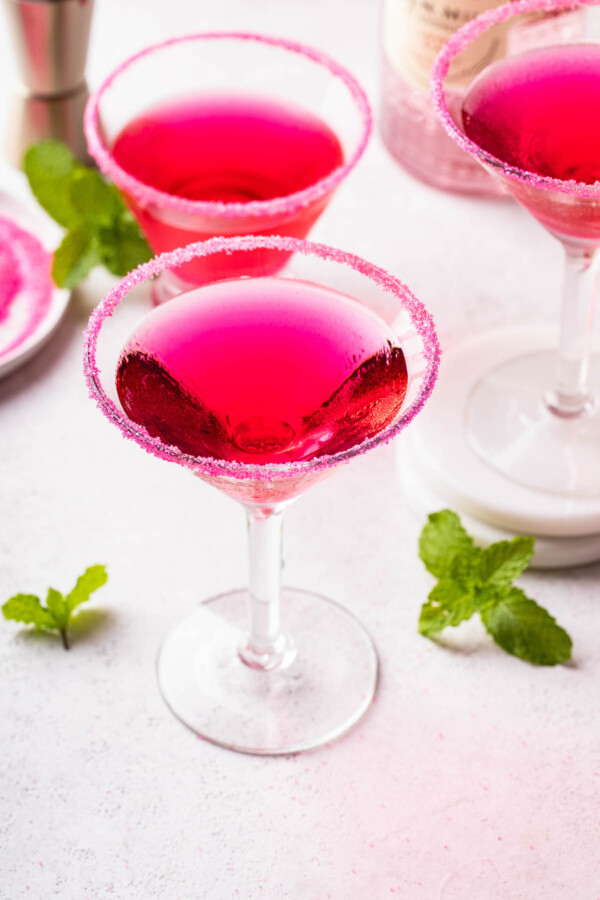 Three pink martinis with sugar rims.