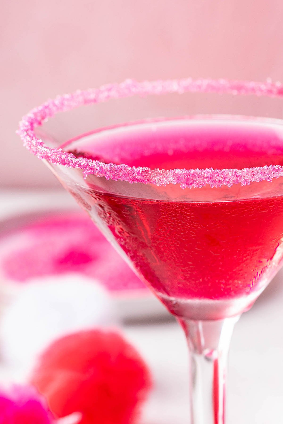 Pink sugar rim on a martini glass filled with a dragon fruit cocktail.