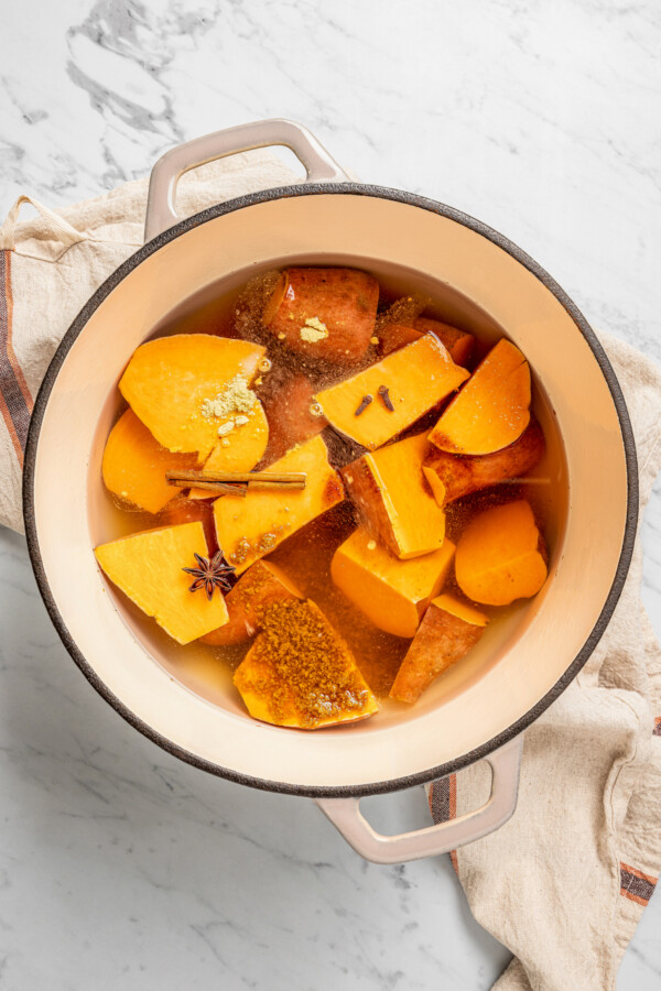 Sweet potatoes in water with seasonings and sugar in a pot.